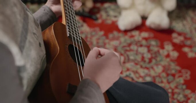 Boy Play Music on Ukulele Instrument in Home Studio. 4K 10-bit