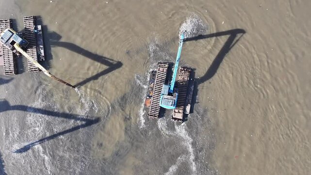 Aerial view The blue and yellow excavator is working to dig and clean the river from mud and rubbish, removing it to the edge of the river middle city 