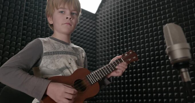 Boy Play Music on Ukulele Instrument in Home Studio. 4K 10-bit