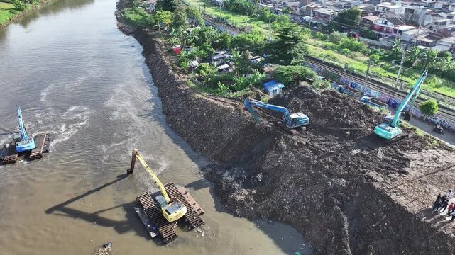 Aerial view The blue and yellow excavator is working to dig and clean the river from mud and rubbish, removing it to the edge of the river middle city 