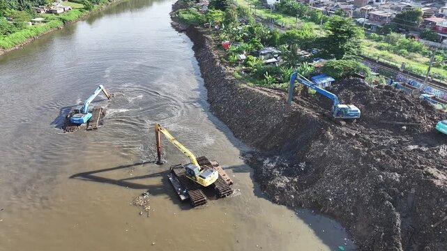 Aerial view The blue and yellow excavator is working to dig and clean the river from mud and rubbish, removing it to the edge of the river middle city 