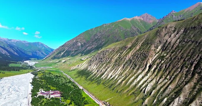 Cinematic aerial view of a winding road and a mountain valley with steep slopes in Xinjiang, China