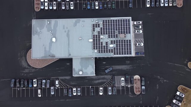 Top View of a commercial auto dealership building in Halifax covered with a large grid-tied solar panel system. Nova Scotia, Canada, renewable energy on industrial rooftop 4K.