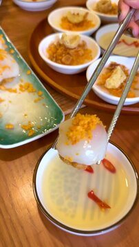 Dipping Vietnamese Banh Beo Steamed Rice Cake into Fish Sauce with Chopsticks