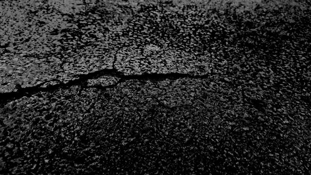  Dramatic black and white grunge texture featuring large deep crack across gritty cement surface. Weathered dark asphalt background with detailed stone grains and industrial fractured patterns