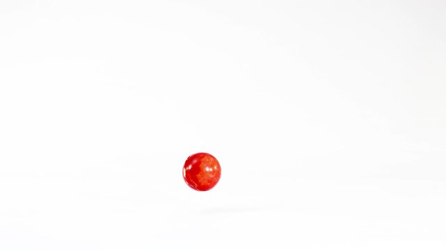 Bright Red Rubber Ball Bouncing on a Solid White Background