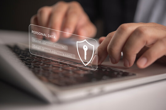 Businessman hands typing laptop keyboard displaying personal data hologram shield icon concept cybersecurity privacy data protection internet information encryption network safety compliance.