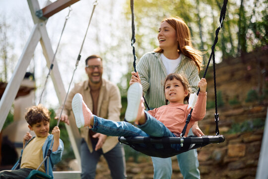 Happy family spending time at playground in spring day.