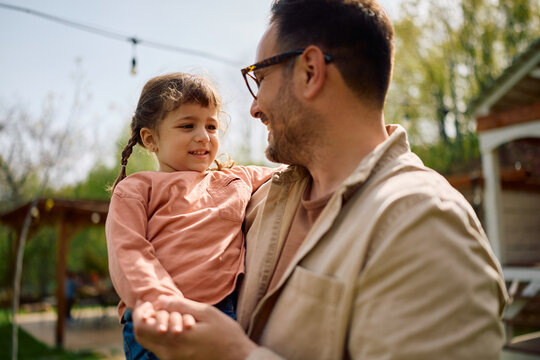 Small girl and her father enjoying in springtime in backyard.