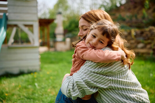 Affectionate mother and daughter embracing in spring day outdoors.