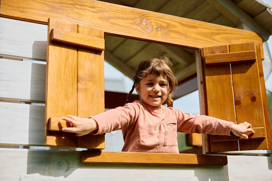 Happy little girl having fun on playground and looking at camera.
