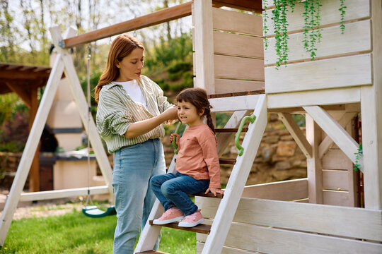 Small girl and her mother enjoying spring day at playground.