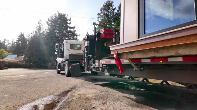 Heavy haul truck transporting a small building with red warning flag waving