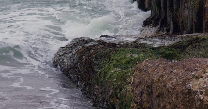 mid shot of waves lapping over old concrete next to Shoreham harbour