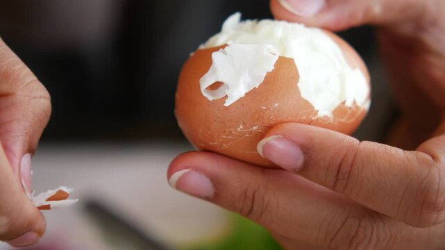 Person peeling a hard-boiled egg at a kitchen table