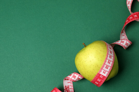 Measuring tape, apple on a colored background
