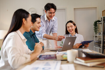 Fototapeta premium Asian business team collaborating on project using laptop in office