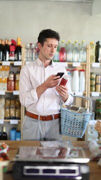 European scans the qr code on a bottle of natural beetroot smoothie. Man came to the supermarket for a smoothie for his healthy diet. High quality 4k footage