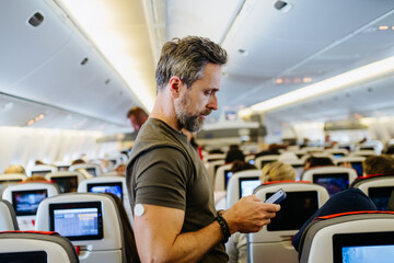Passenger with diabetes placing carry on luggage in overhead compartment.