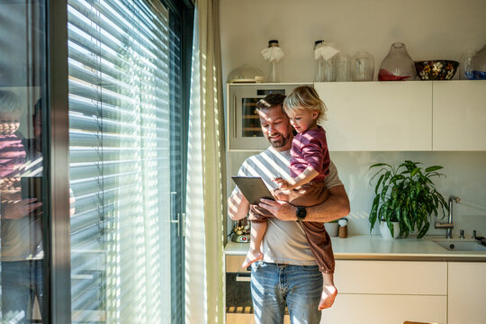 Father showing smart home control to toddler while managing exterior shading system.
