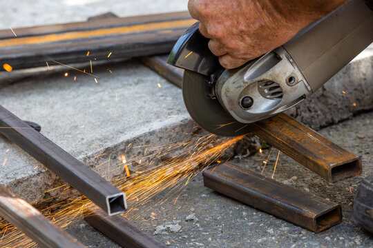 Close-up of angle grinder cutting metal bars outdoors