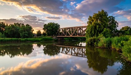 Fototapeta premium A serene river scene with a bridge and trees at sunset