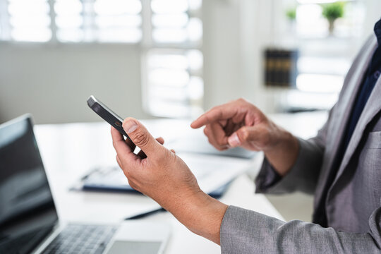 Professional business man in office holding mobile cellphone. technology device at work.