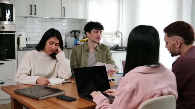 Young sleepy woman struggling to stay awake while studying with friends around a kitchen table