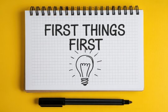 First things first concept on a notebook with a pen on a yellow background