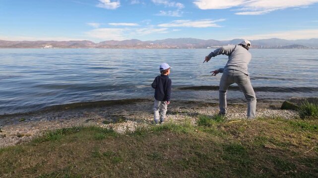 Father and son skipping stones by the lake
