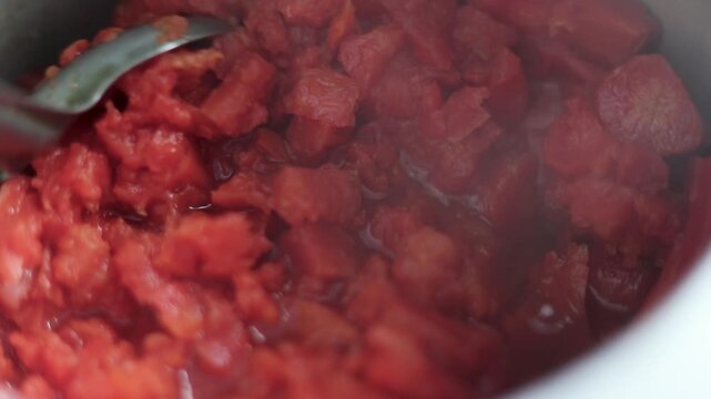 Close-up of gajar ka halwa being cooked with visible steam and rich texture in a pan. Traditional Indian sweet dish preparation, hot dessert, rural lifestyle, poverty, slum village poor india concept.