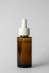 Fototapeta premium Amber glass bottle with dropper on white background, skincare product
