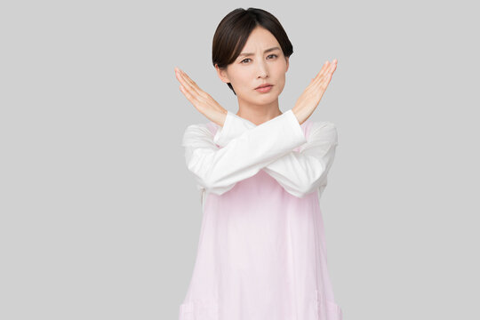 両手でバツ印を作るエプロン姿の女性（禁止・拒絶・NGイメージ）