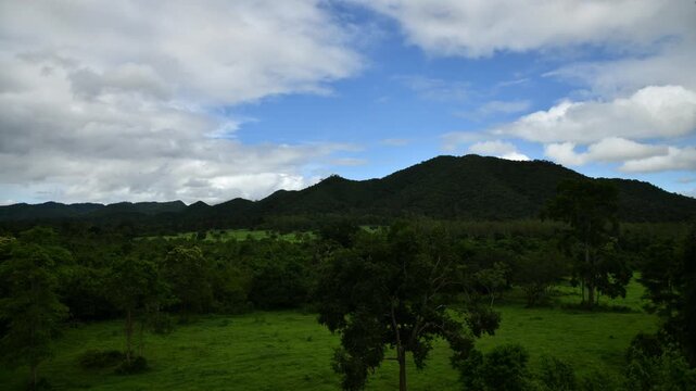 Summer scenery of mountainous countryside. forested mountain ridge in the distance beneath a blue sky with fluffy clouds.