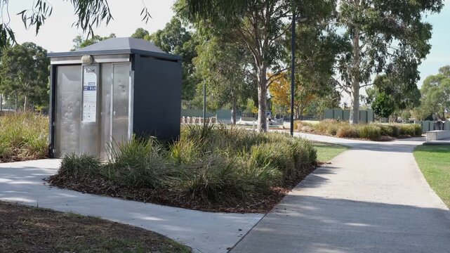 A contemporary freestanding public toilet amenity unit with stainless steel automatic door&nbsp;beside a concrete pathway in a suburban park in Melbourne Australia.