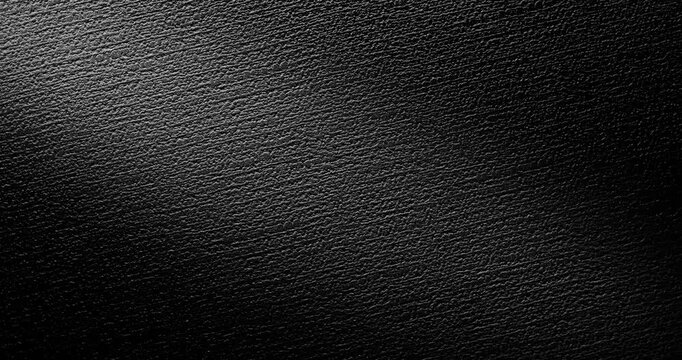 Seamless Abstract black texture.  A slow, smooth loop rotation of a dark, rough surface, gently rotating under the light, creating subtle highlights.