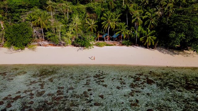 A turqouse colored ocean with clear water at Koh Kradan, a tropical island in Trang, Thailand, and a coral reef in front of a tropical island