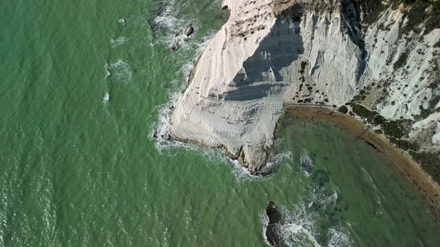 Aerial view of white cliffs meeting turquoise sea, showcasing the gradual erosion of the shoreline and the dynamic interaction of land and water in a coastal landscape