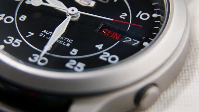 Macro close up of an automatic mechanical field watch with moving arms
