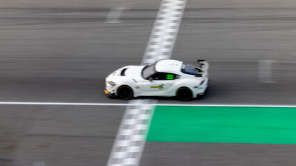 Fototapeta premium Motion blur, Race car racing on speed track, race car on road crossing start and finish line, Target business achieve and victory concept. .
