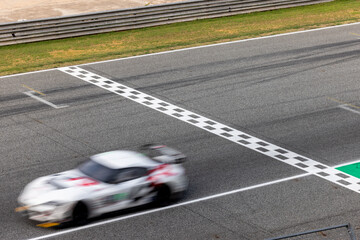 Fototapeta premium Motion blur, Race car racing on speed track, race car on road crossing start and finish line, Target business achieve and victory concept.