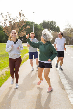 Happy multi generational group giving thumbs up jogging