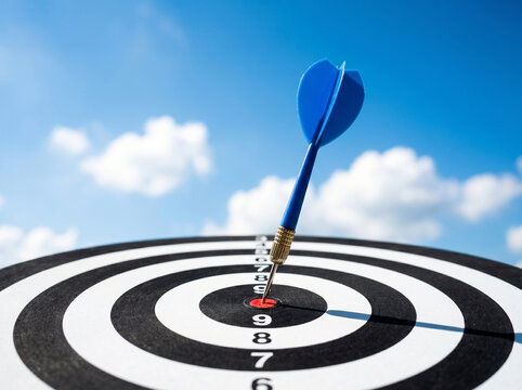 A striking blue dart precisely hitting the bullseye of a dartboard symbolizing perfect aim strategic planning and ultimate achievement under an expansive blue sky with wispy clouds.