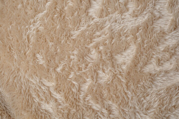 Close up view of soft light brown fluffy cozy warm texture fabric material surface background © reddish