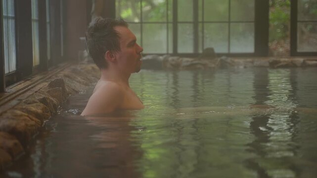 Man relaxing in traditional Japanese onsen bath