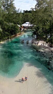 Discover Koh Kood Island in Thailand, where turquoise waters meet soft sandy beaches. Two people stroll through shallow waters, enjoying the tranquility and natural beauty under the sun.