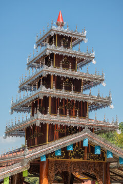 Ornate multi-tiered wooden temple architecture with intricate silver filigree details and a vibrant red spire under a clear day, characteristic of Lanna style, Wat Chet Yot, Chiang Mai.