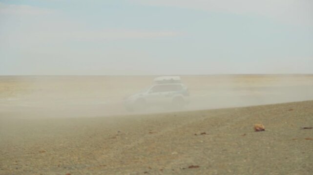 Adventurous Rugged Drive. Offroad Vehicle Swiftly Navigates Rocky Salt Plains Amid Dust And Fog. Rugged Vehicle Surges Across Rugged Salt Flats With Dust Clouds And Beams Illuminating Haze