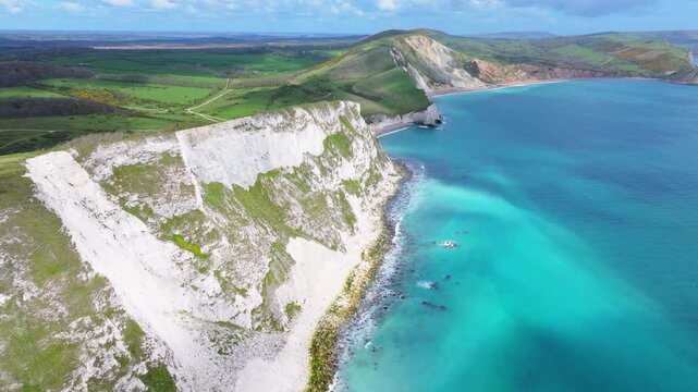 Ascending aerial shot travelling along Mupe Bay and chalk cliffs and along the Jurassic Coastline of Dorset