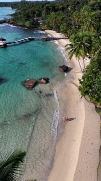 A couple experience the beauty of Koh Kood Island, Thailand, where soft sands meet clear turquoise waters. The calm beach invites relaxation and exploration of this tropical paradise.